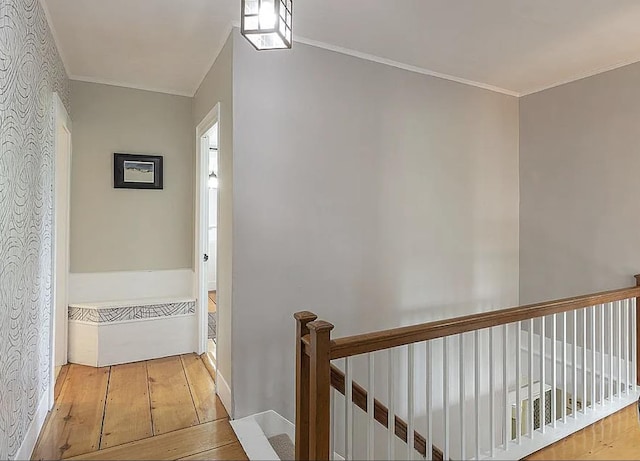 hall featuring an upstairs landing, hardwood / wood-style flooring, and crown molding