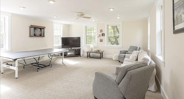 living area with a wealth of natural light, light colored carpet, crown molding, and baseboards