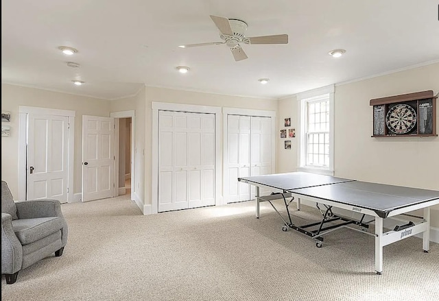 rec room featuring baseboards, a ceiling fan, light colored carpet, and crown molding