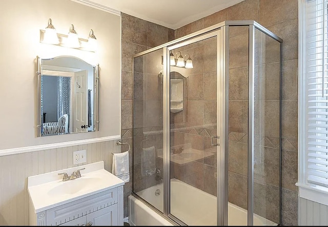 bathroom featuring a wainscoted wall, shower / bath combination with glass door, and vanity