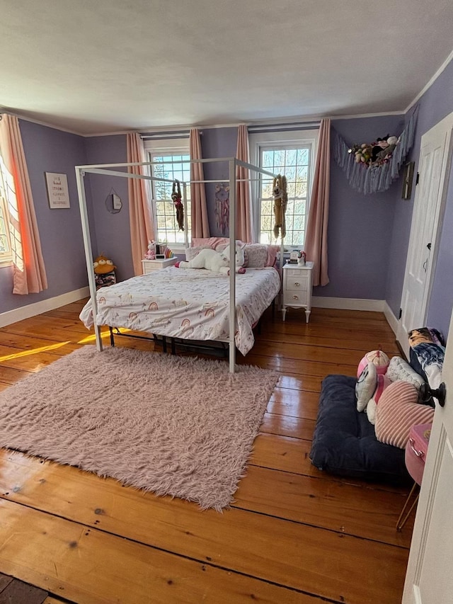 bedroom featuring crown molding, hardwood / wood-style floors, multiple windows, and baseboards