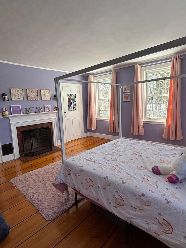 bedroom featuring hardwood / wood-style floors, multiple windows, and a fireplace