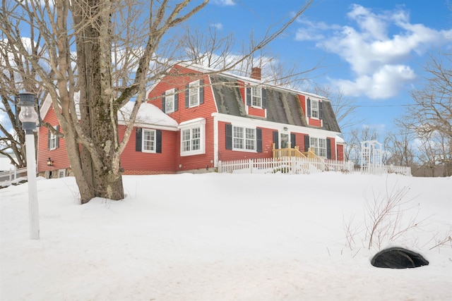 view of snow covered exterior featuring a chimney and a gambrel roof