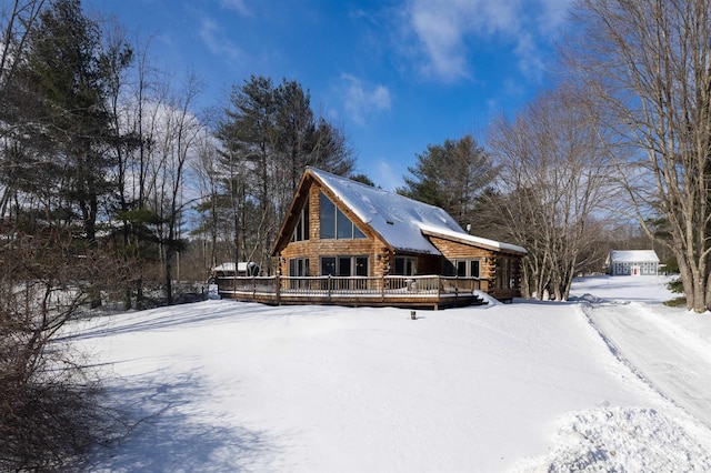 snow covered back of property featuring a deck and log siding