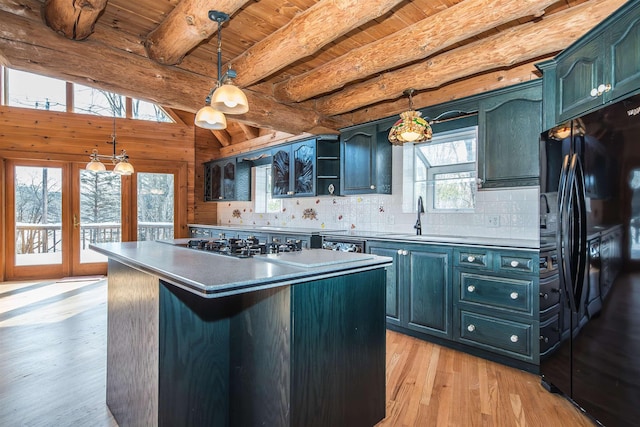 kitchen featuring tasteful backsplash, lofted ceiling with beams, light wood-style flooring, freestanding refrigerator, and a sink