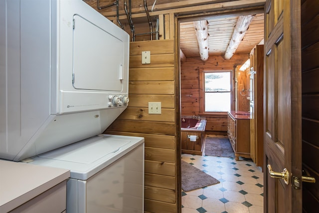 laundry area featuring wooden walls, laundry area, stacked washer / dryer, wood ceiling, and light floors