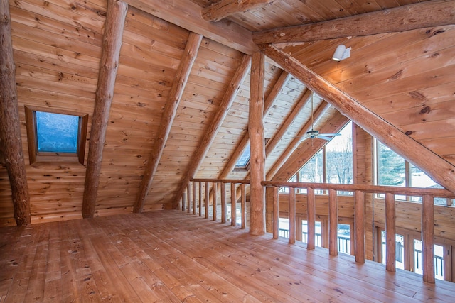 additional living space with vaulted ceiling with beams, wood ceiling, ceiling fan, wood walls, and hardwood / wood-style floors