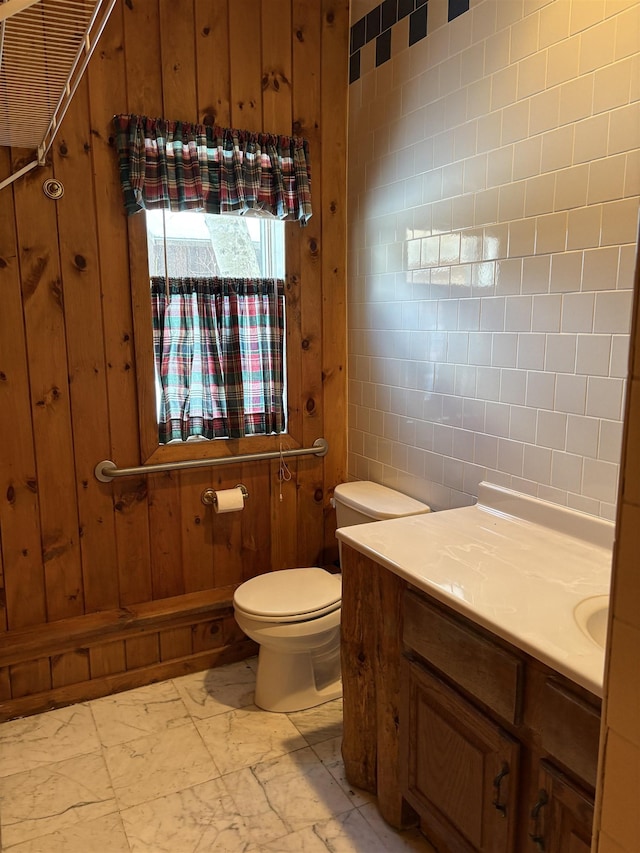 bathroom featuring marble finish floor, wood walls, vanity, and toilet