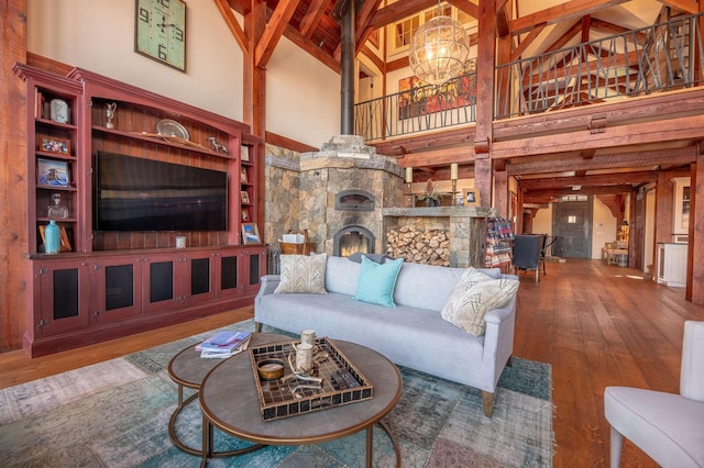 living area with high vaulted ceiling, a notable chandelier, a fireplace, beamed ceiling, and wood-type flooring