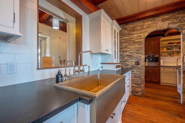 kitchen featuring dark countertops, dark wood-style flooring, oven, and a sink