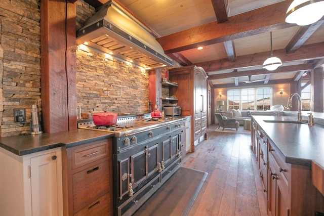 kitchen with range with two ovens, custom range hood, open floor plan, hardwood / wood-style floors, and a sink