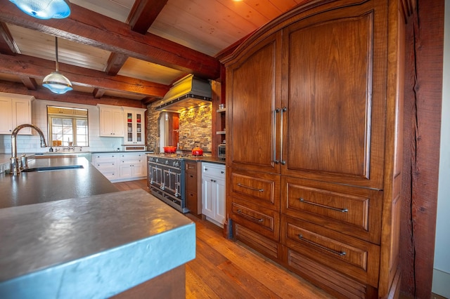 kitchen with white cabinets, range with two ovens, dark wood-style floors, a sink, and beam ceiling