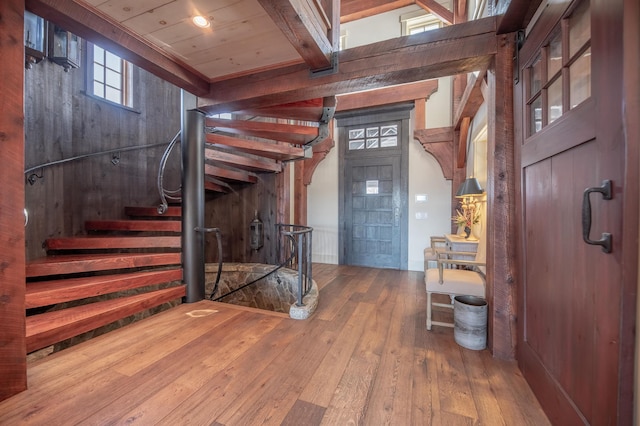 entrance foyer featuring wood-type flooring, beam ceiling, and stairs