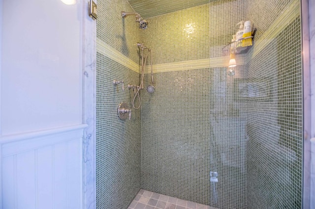 full bathroom with wainscoting and tiled shower