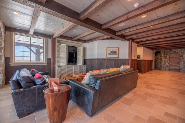 living room with a wainscoted wall, wood ceiling, wooden walls, and beamed ceiling