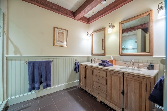 full bath featuring wainscoting, tile patterned flooring, a sink, and beamed ceiling