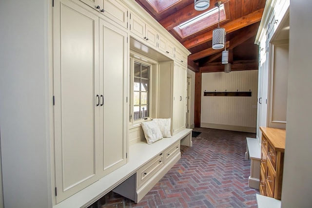 mudroom featuring brick floor, beamed ceiling, and a skylight