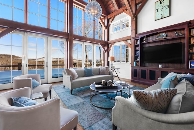 living area featuring beam ceiling, an inviting chandelier, wood ceiling, wood finished floors, and high vaulted ceiling