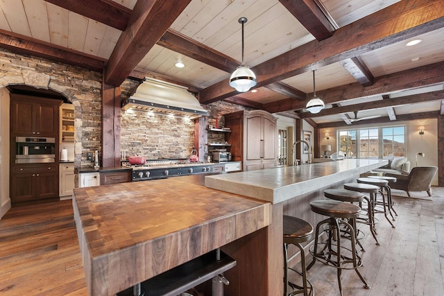 kitchen featuring dark wood-style floors, wooden counters, custom exhaust hood, and stainless steel appliances