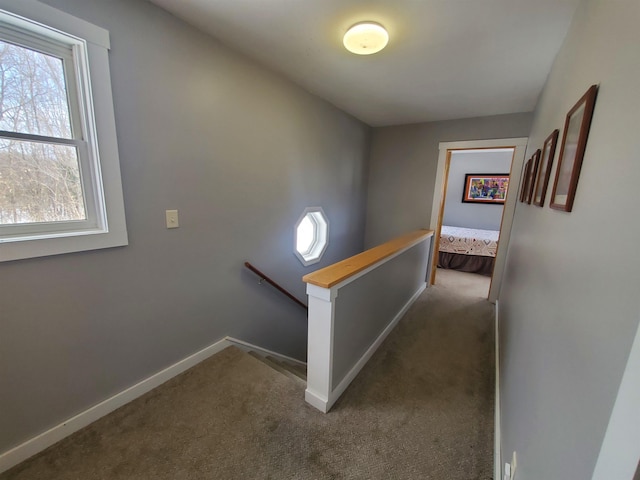 corridor with baseboards, dark carpet, and an upstairs landing