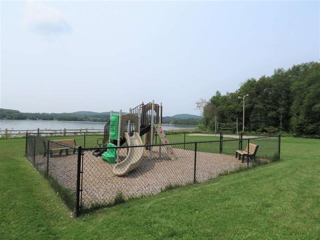 community play area with a lawn, a water view, and fence