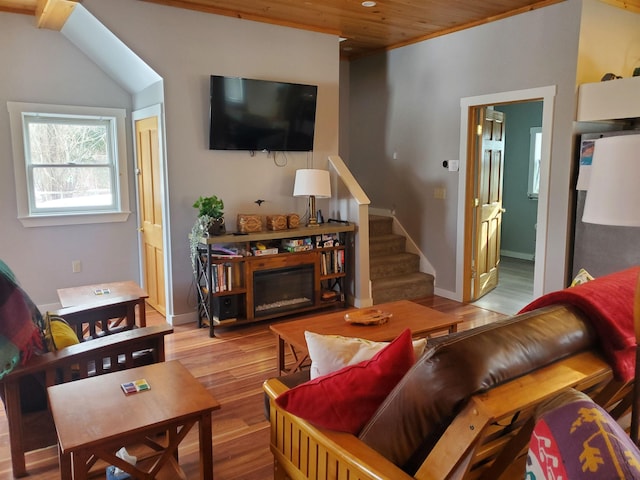 living room featuring stairs, baseboards, wood finished floors, and a glass covered fireplace