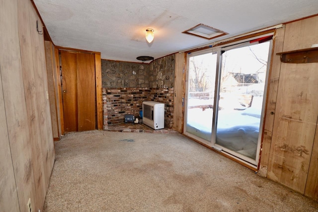 unfurnished living room featuring carpet floors, wood walls, a textured ceiling, and heating unit