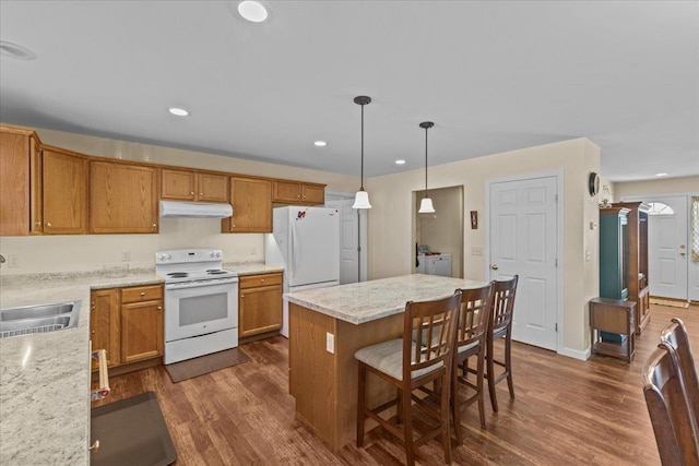 kitchen featuring a sink, white appliances, under cabinet range hood, and dark wood-type flooring