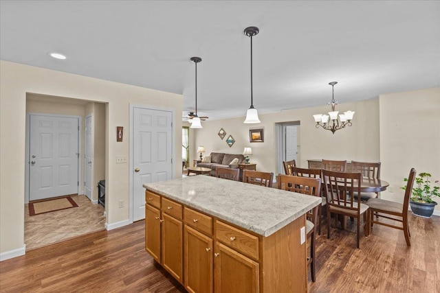 kitchen featuring a center island, dark wood finished floors, light countertops, hanging light fixtures, and baseboards