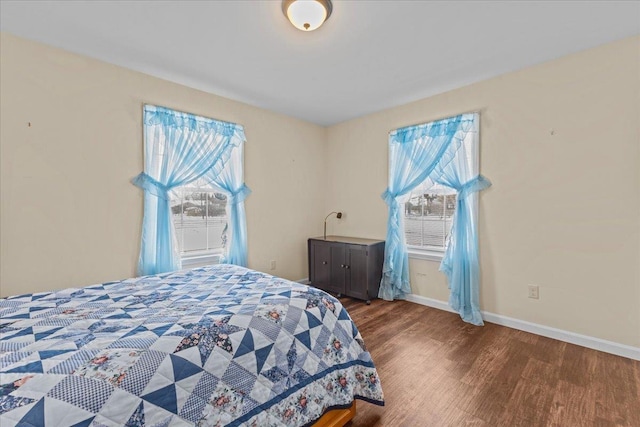 bedroom with multiple windows, baseboards, and wood finished floors