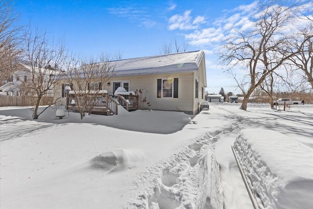 snow covered back of property featuring a deck