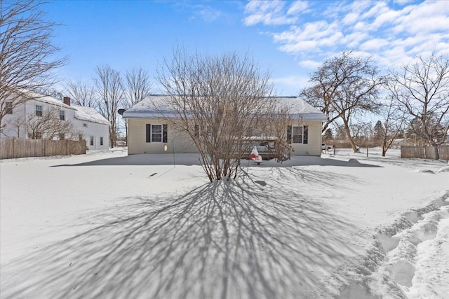 snow covered rear of property with fence