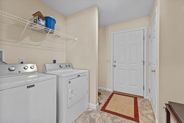 washroom featuring light tile patterned floors, laundry area, washing machine and clothes dryer, and baseboards