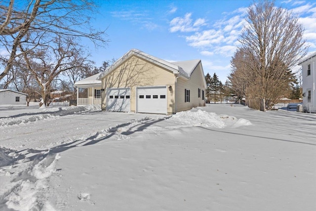 view of snowy exterior featuring driveway and an attached garage