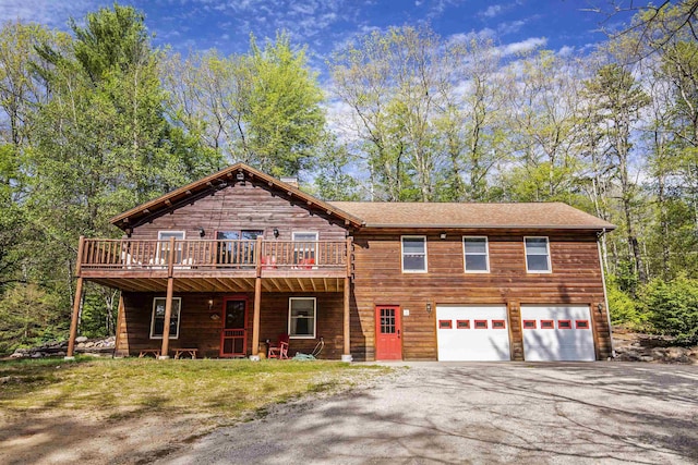 log home with aphalt driveway, a wooden deck, and an attached garage