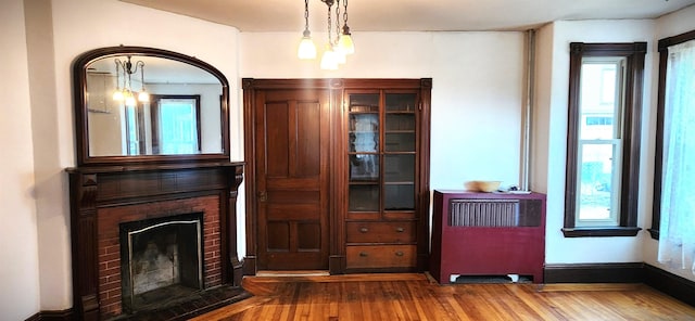 interior space with a brick fireplace, wood finished floors, and a healthy amount of sunlight