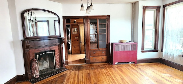 interior space featuring a fireplace with flush hearth, plenty of natural light, baseboards, and wood finished floors