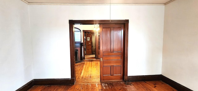 spare room featuring a fireplace, baseboards, hardwood / wood-style floors, and ornamental molding