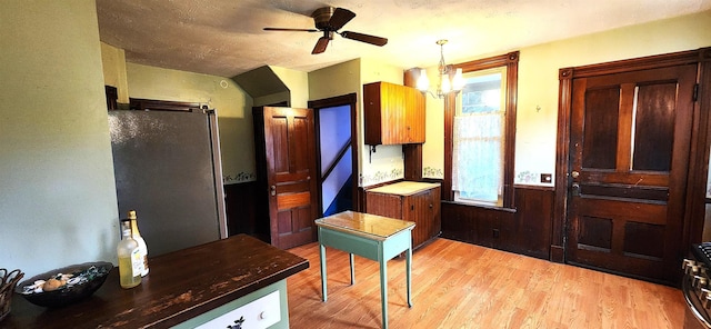 interior space with light wood finished floors, a wealth of natural light, and ceiling fan with notable chandelier