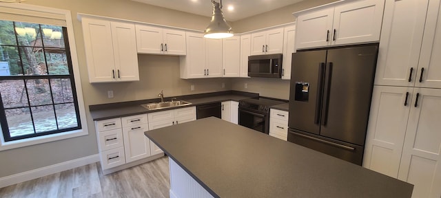 kitchen with black appliances, dark countertops, a sink, and white cabinets