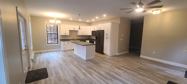 kitchen with dark countertops, black appliances, a kitchen island, and baseboards