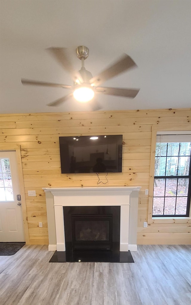 room details with ceiling fan, wood finished floors, a fireplace with flush hearth, and wooden walls