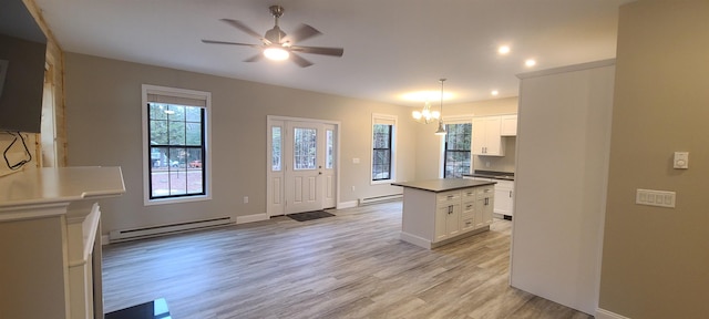 kitchen with light wood-type flooring, a baseboard radiator, white cabinetry, and a center island