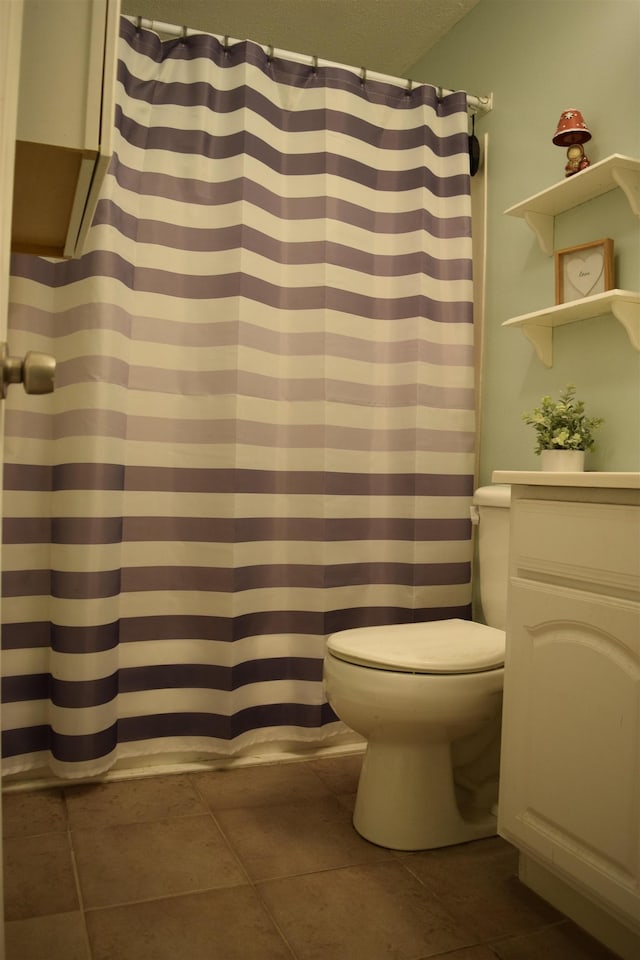 bathroom featuring a textured ceiling, curtained shower, toilet, and tile patterned floors