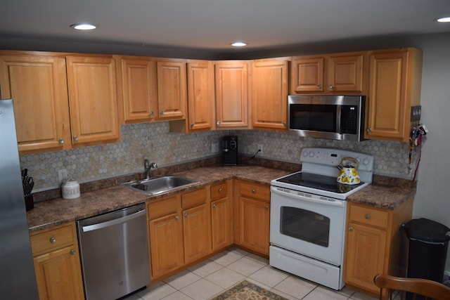 kitchen with stainless steel appliances, dark countertops, a sink, and light tile patterned floors