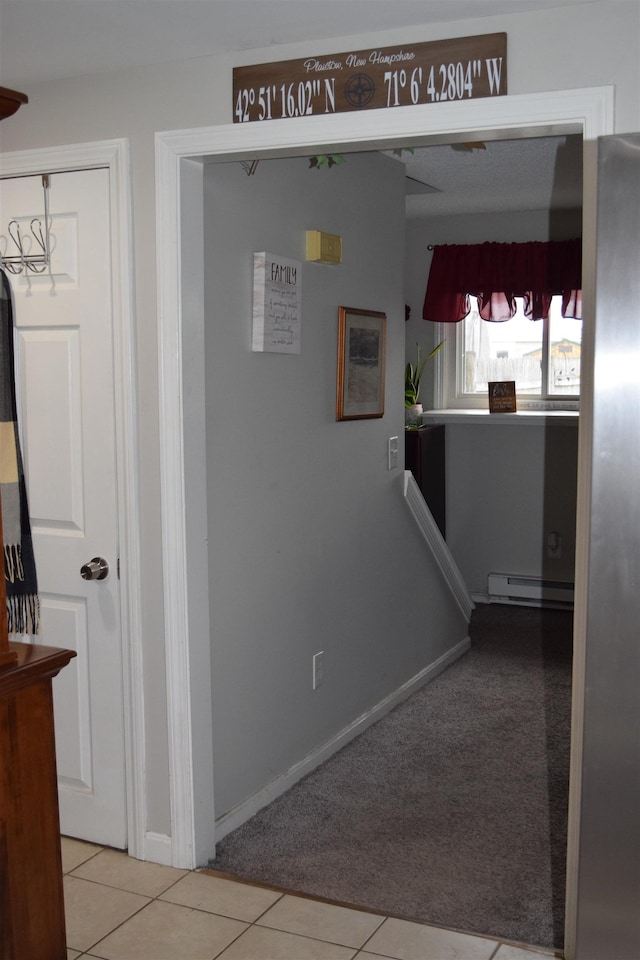 corridor with carpet floors, baseboards, baseboard heating, and tile patterned floors