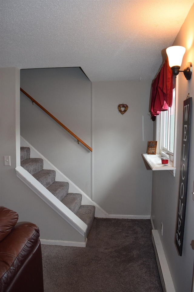 stairway with a textured ceiling, a baseboard radiator, carpet flooring, and baseboards