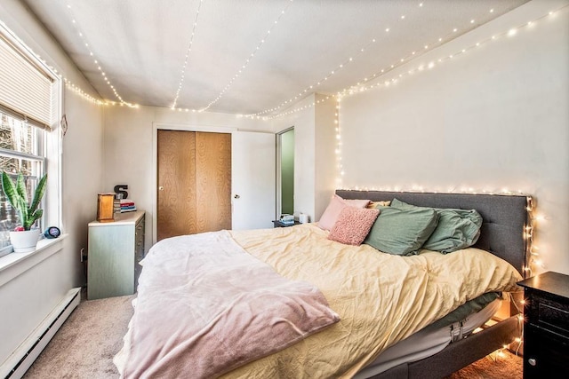 carpeted bedroom with a baseboard heating unit and a closet