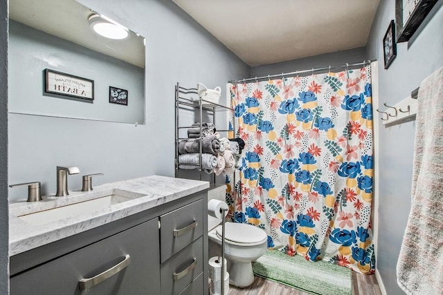 bathroom with curtained shower, vanity, toilet, and wood finished floors