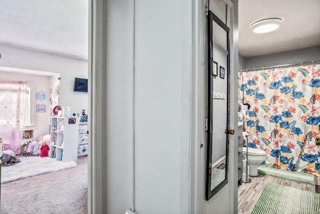 bathroom featuring toilet, curtained shower, and wood finished floors